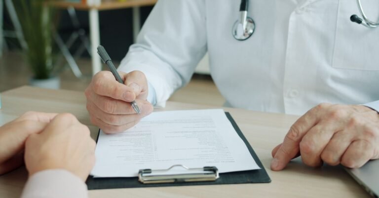 Médecin en blouse blanche remplissant un document avec un patient lors d’une consultation