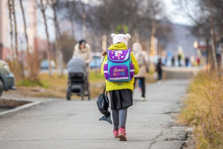 Enfant marchant sur un trottoir avec son cartable scolaire sur le dos