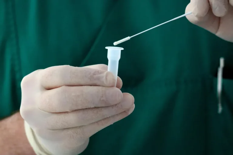 Comment choisir un dispositif de dépistage de drogue salivaire ? Soignant ganté tenant un écouvillon et un tube de prélèvement salivaire